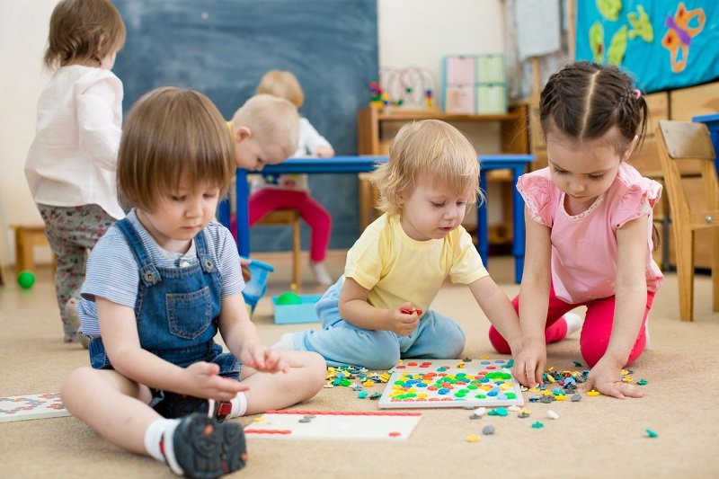 kids or children playing mosaic game in kindergarten room
